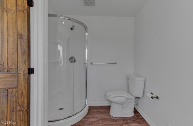 bathroom featuring wood finished floors, visible vents, toilet, and a stall shower
