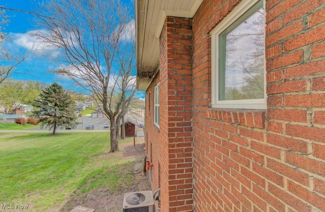 view of home's exterior featuring central air condition unit, brick siding, and a lawn