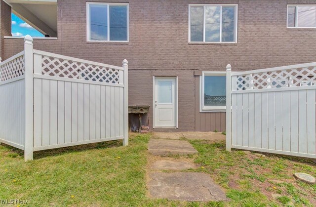 back of house featuring brick siding, fence, and a yard
