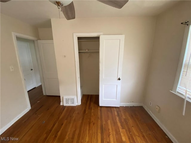 unfurnished bedroom with wood finished floors, visible vents, a closet, baseboards, and ceiling fan