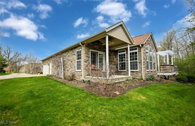 exterior space with a lawn, driveway, and stone siding