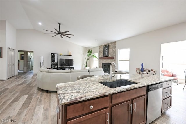 kitchen with a wealth of natural light, stainless steel dishwasher, a sink, and a fireplace