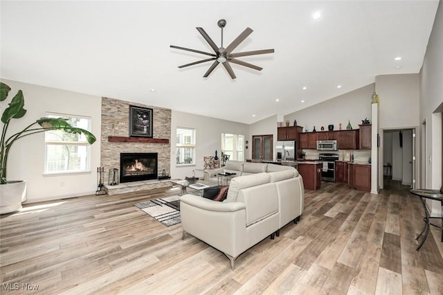 living area featuring recessed lighting, a stone fireplace, a ceiling fan, light wood-style flooring, and high vaulted ceiling