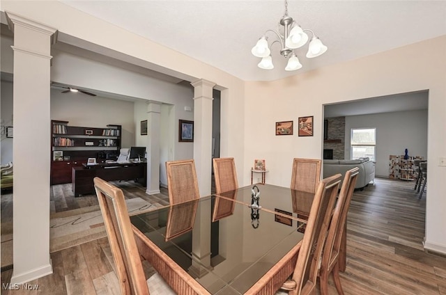 dining space featuring baseboards, a notable chandelier, wood finished floors, and ornate columns