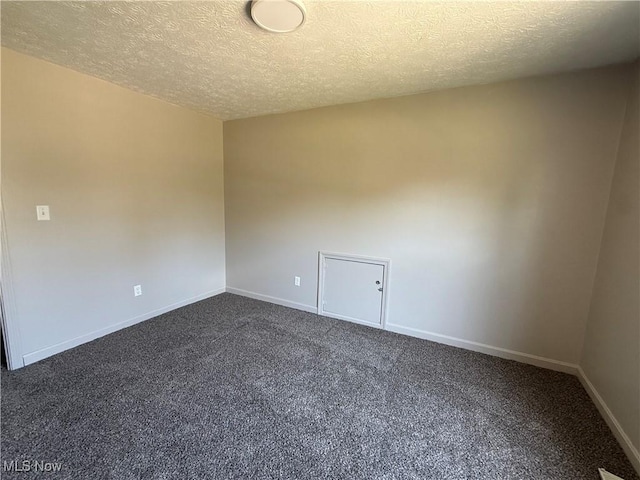 unfurnished room with dark carpet, a textured ceiling, and baseboards