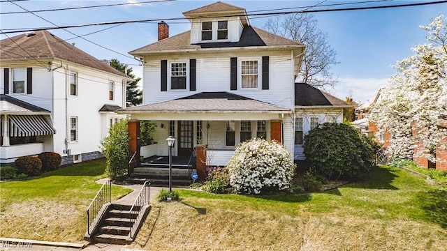 view of front of house with a chimney, covered porch, a front yard, and roof with shingles