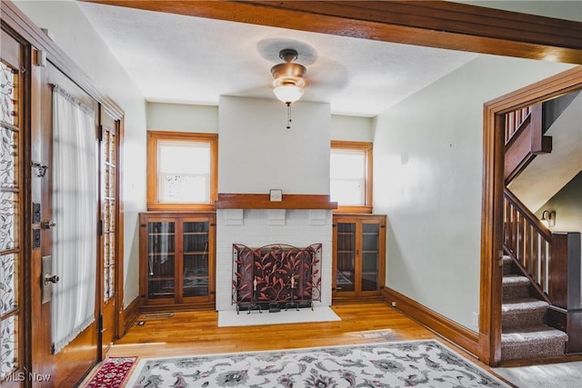 living area with baseboards, wood finished floors, stairway, ceiling fan, and a fireplace