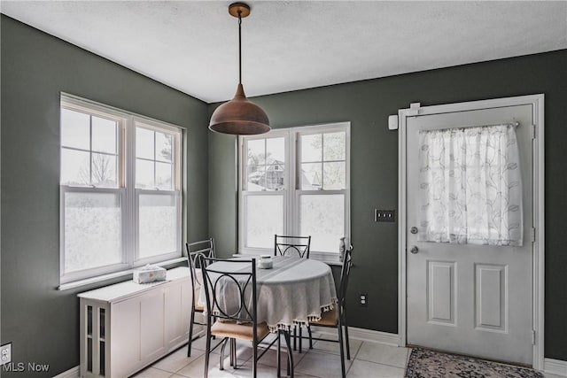 dining room with baseboards, light tile patterned flooring, and a textured ceiling