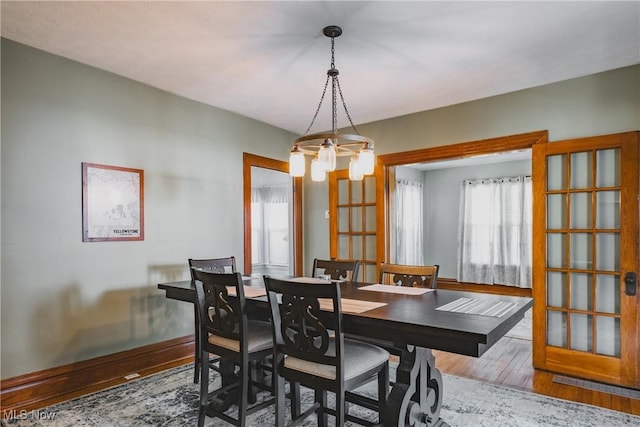 dining space featuring baseboards, wood finished floors, and an inviting chandelier