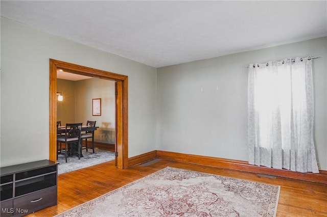 unfurnished room featuring visible vents, baseboards, and wood finished floors