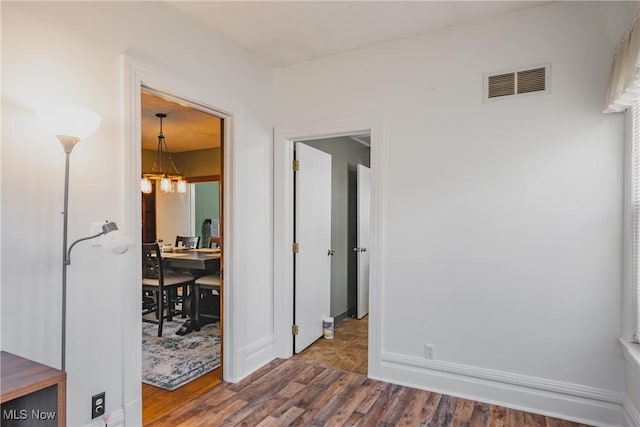 interior space with a chandelier, wood finished floors, visible vents, and baseboards