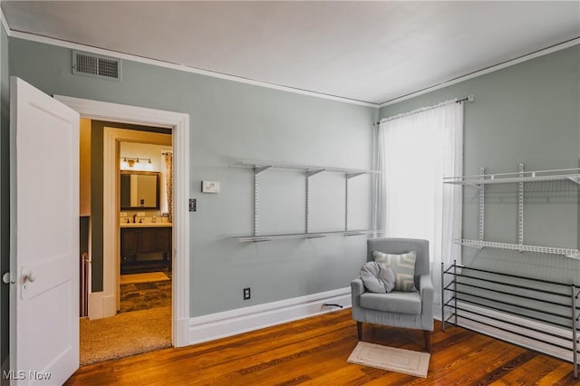 sitting room with baseboards, wood finished floors, visible vents, and ornamental molding