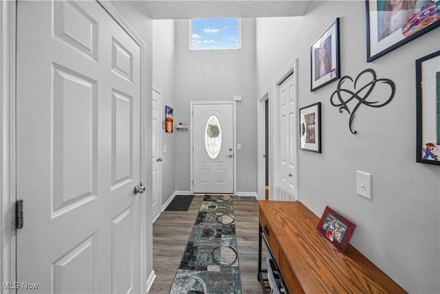 entryway featuring dark wood finished floors, baseboards, and a high ceiling