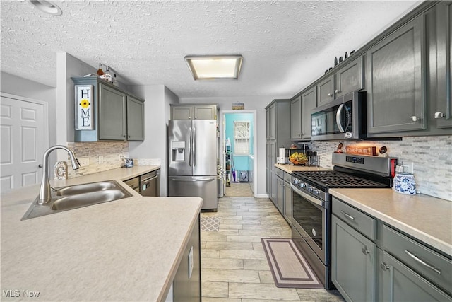 kitchen featuring backsplash, stainless steel appliances, light countertops, and a sink
