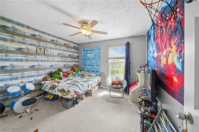 carpeted bedroom with wooden walls, a textured ceiling, and ceiling fan