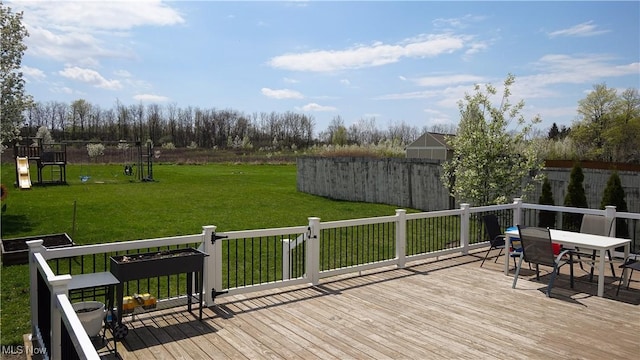 wooden terrace with a lawn, outdoor dining area, and fence