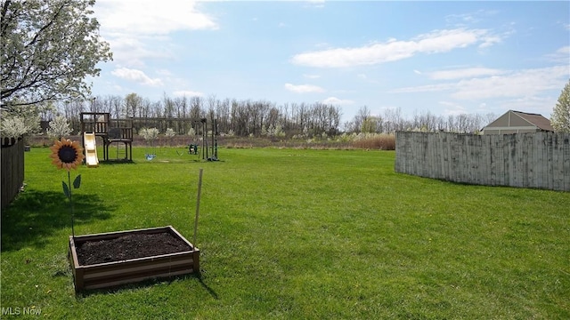 view of yard with fence, a garden, and a playground