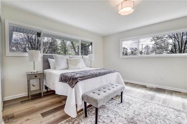 bedroom with wood finished floors, visible vents, and baseboards