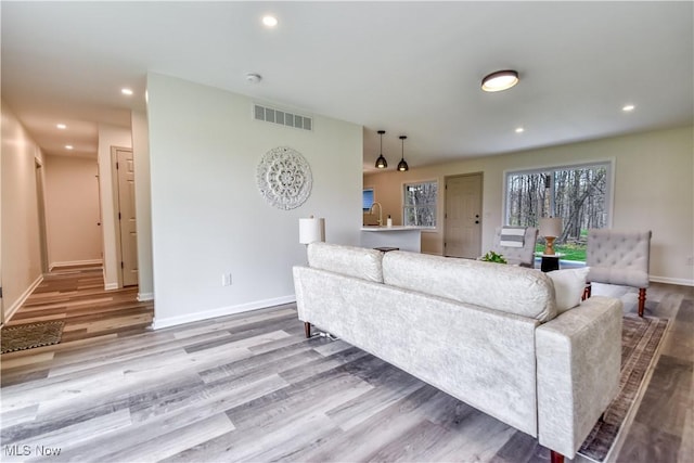 living room featuring recessed lighting, wood finished floors, visible vents, and baseboards