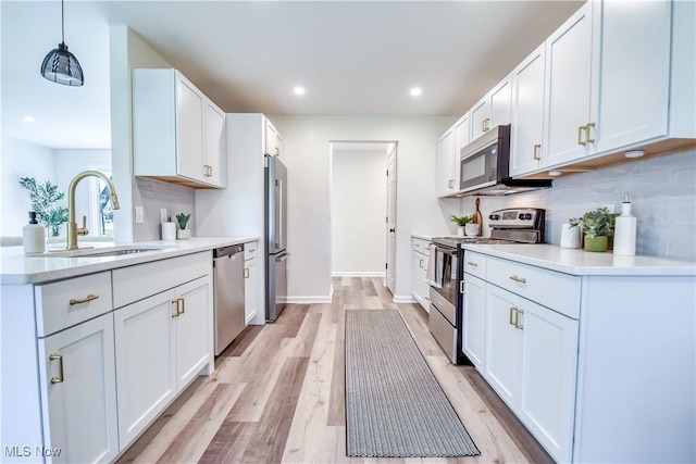 kitchen featuring light wood-type flooring, stainless steel appliances, light countertops, and a sink
