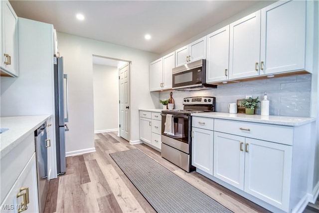 kitchen with recessed lighting, white cabinets, light wood finished floors, stainless steel appliances, and backsplash