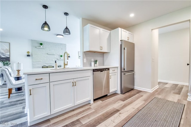 kitchen with light countertops, white cabinetry, stainless steel appliances, and a sink