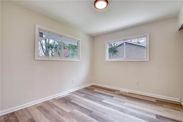 empty room with baseboards, wood finished floors, and visible vents