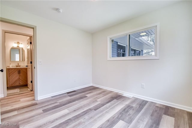 spare room featuring baseboards, light wood-style floors, and a sink