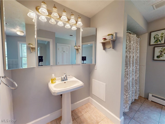 full bathroom with tile patterned flooring, a baseboard heating unit, baseboards, a shower with curtain, and a textured ceiling