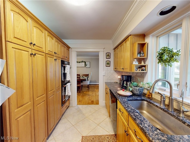 kitchen with a sink, light tile patterned flooring, dark stone counters, black appliances, and ornamental molding