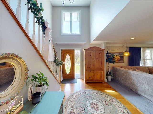 foyer with light wood-style floors, stairway, and a high ceiling