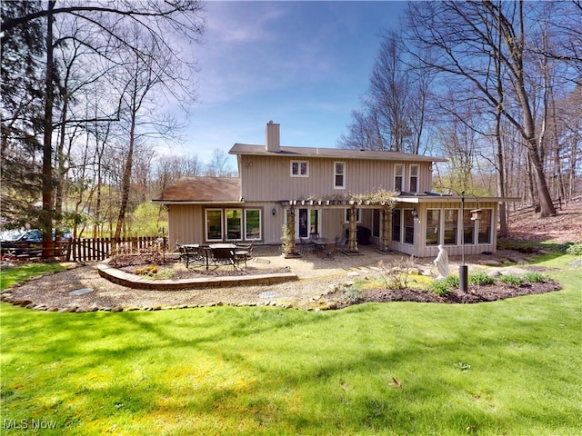 back of property with a chimney, a sunroom, and a patio area