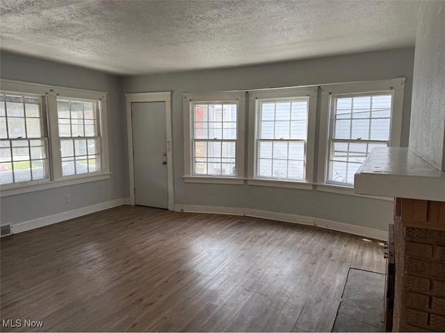 unfurnished living room featuring visible vents, a wealth of natural light, wood finished floors, and a textured ceiling
