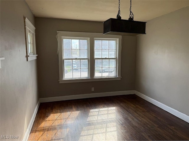 unfurnished dining area with dark wood finished floors and baseboards