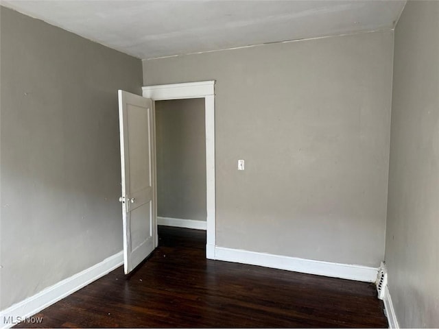 spare room with baseboards and wood finished floors