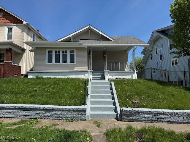 bungalow-style house with a front yard, stairs, covered porch, and fence