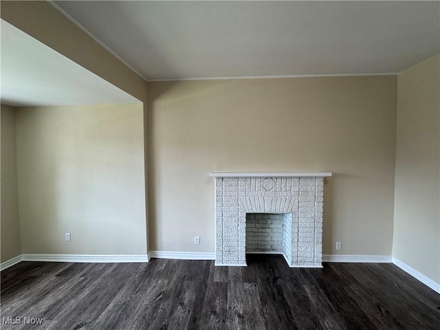 unfurnished living room featuring baseboards and dark wood-style flooring
