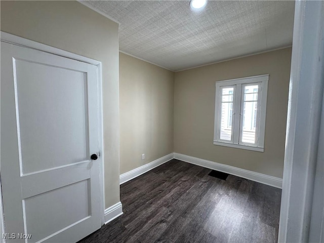 spare room with dark wood finished floors and baseboards