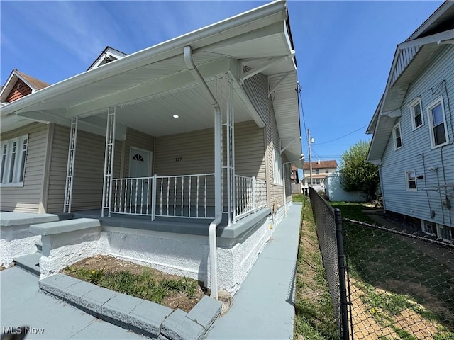 view of side of home with fence and covered porch