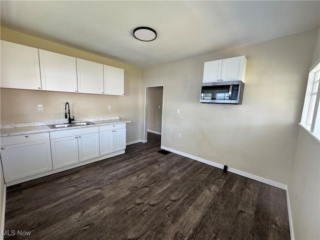 kitchen with dark wood-style floors, baseboards, a sink, and stainless steel microwave