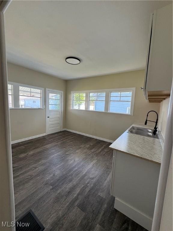 unfurnished living room featuring baseboards, visible vents, dark wood-type flooring, and a sink