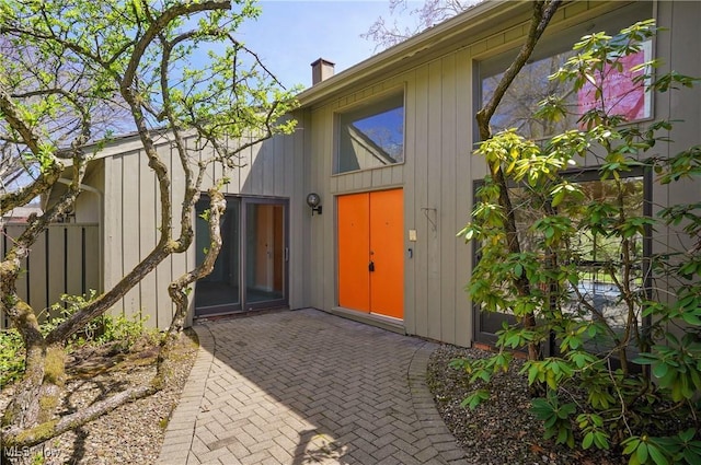 entrance to property featuring a chimney, fence, and a patio area