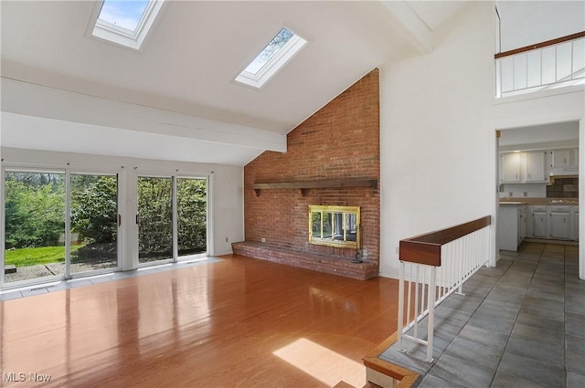 unfurnished living room with a brick fireplace, a skylight, and beam ceiling