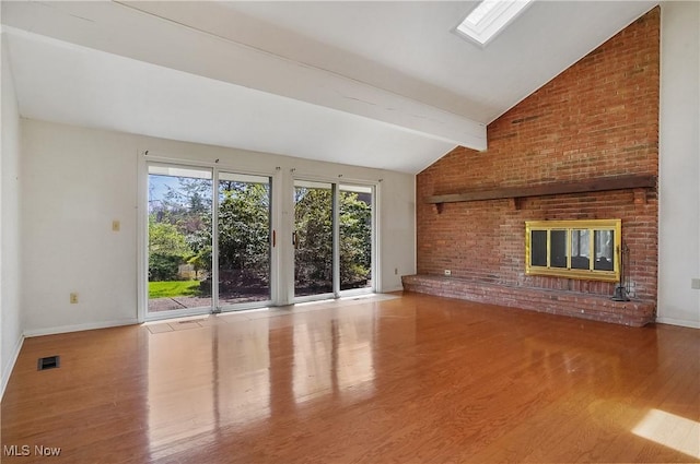 unfurnished living room with visible vents, vaulted ceiling with beams, wood finished floors, and baseboards