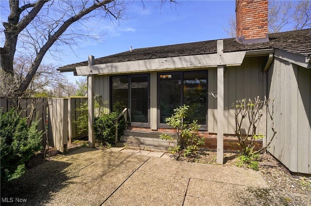 back of property with fence, a chimney, entry steps, and a patio