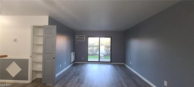 interior space featuring radiator, an AC wall unit, dark wood finished floors, and baseboards