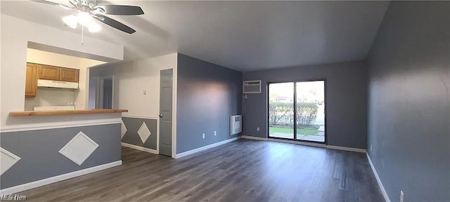 empty room with dark wood-style flooring, a wall unit AC, heating unit, ceiling fan, and baseboards