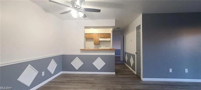 empty room featuring ceiling fan, wainscoting, and dark wood-style flooring