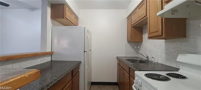kitchen featuring tasteful backsplash, white appliances, brown cabinetry, under cabinet range hood, and a sink