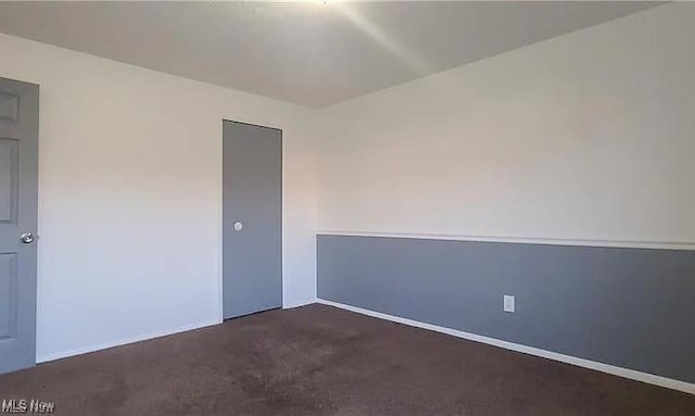 empty room featuring dark carpet and baseboards